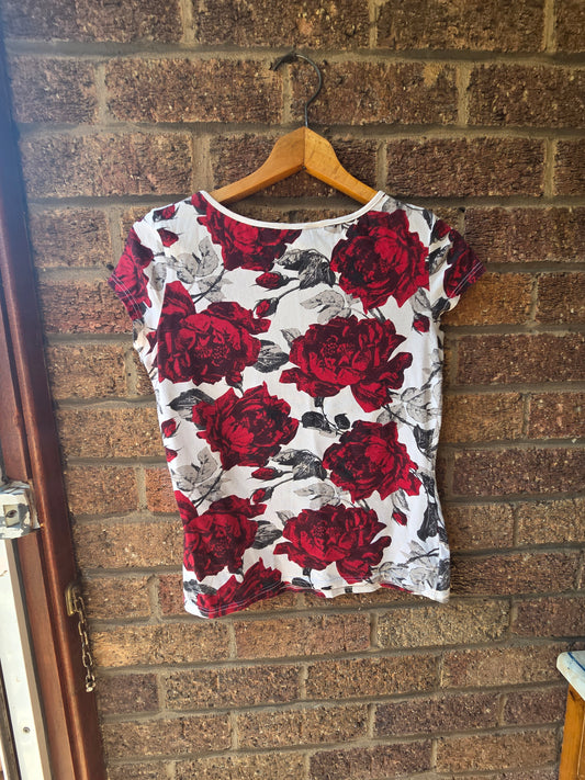 Dorothy Perkins red rose print cap sleeve top on wooden hanger against brick wall, back view
