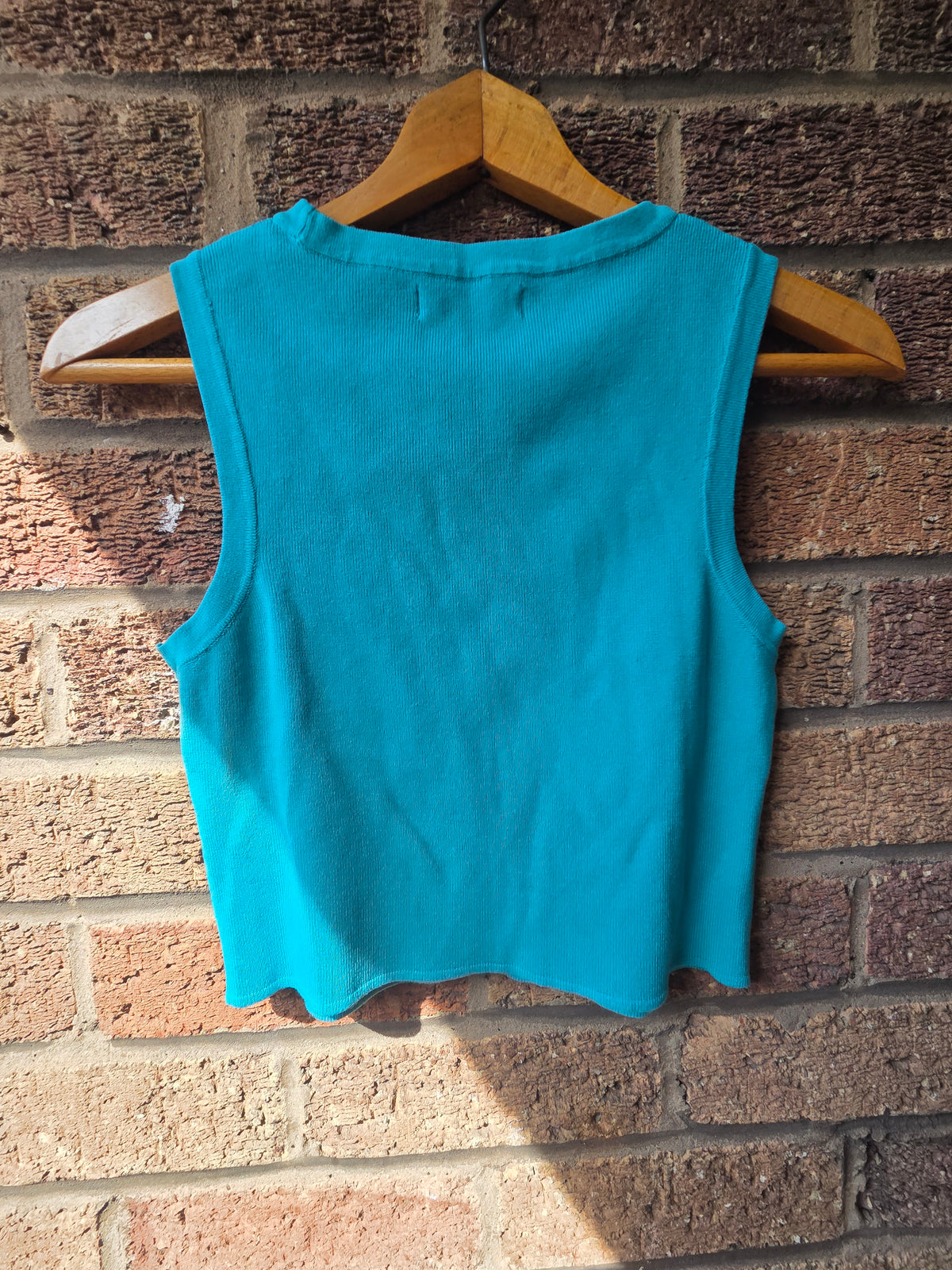 Close-up of Primark Cares label showing size M — inside neck of teal crop top