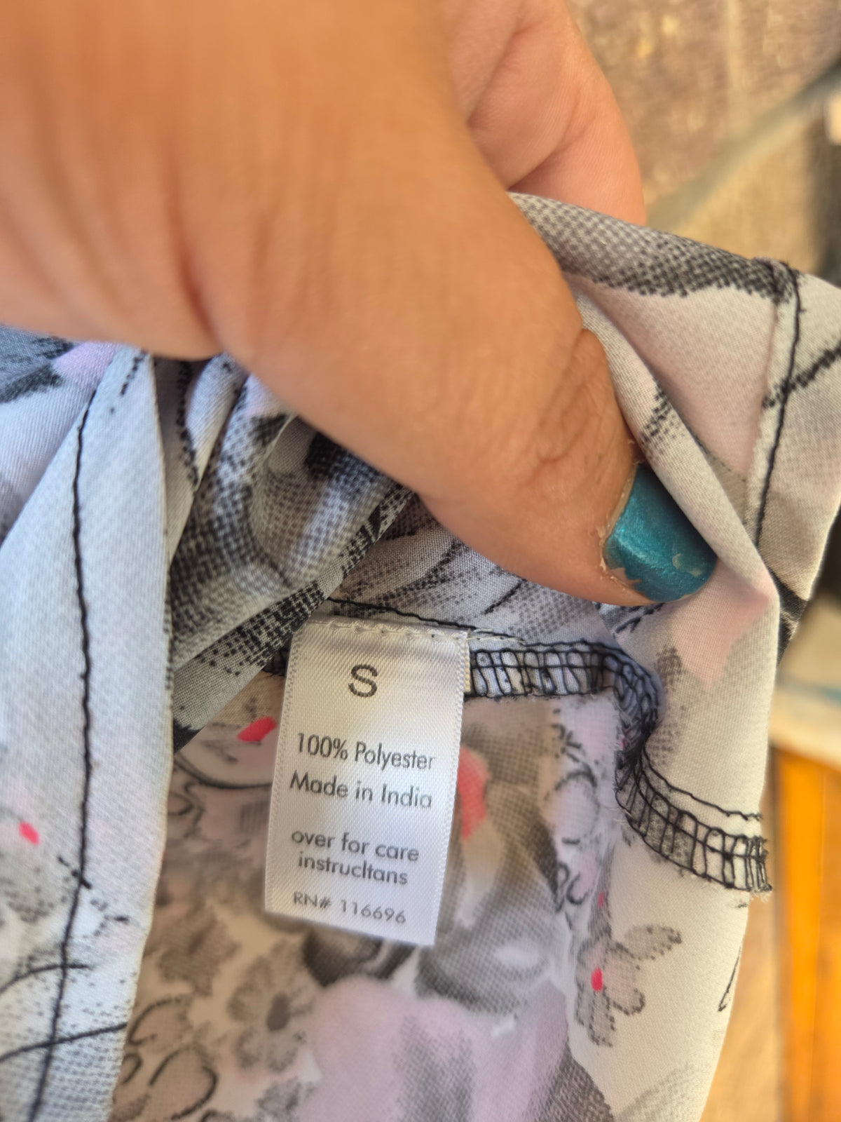 Close-up of care label showing size S, 100% polyester, made in India