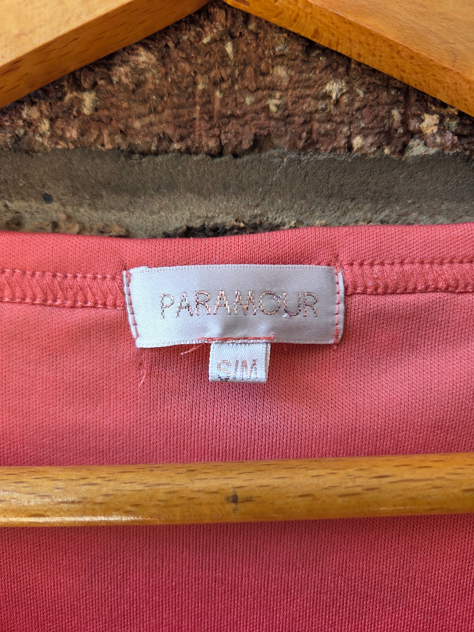 Close-up of Paramour brand label and S/M size tag inside neckline of coral lace top