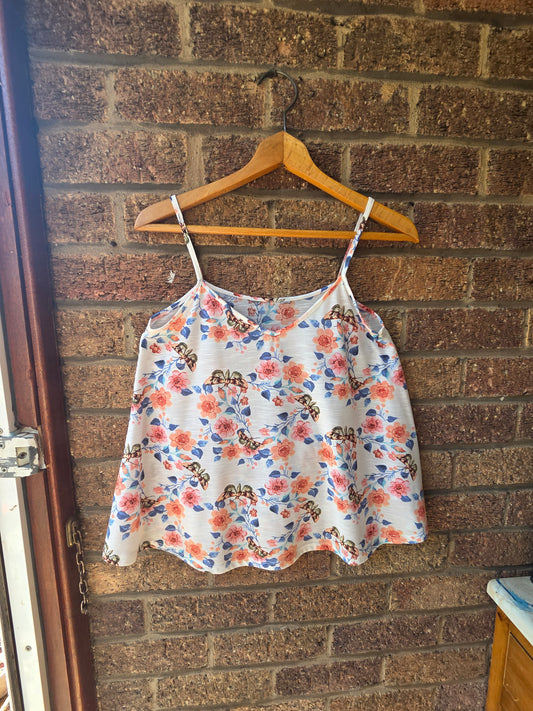Dorothy Perkins cream butterfly floral cami top on wooden hanger against brick wall, front view