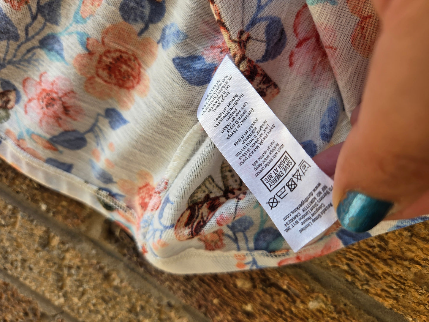 Close-up of care label in side seam showing wash instructions for Dorothy Perkins floral cami top