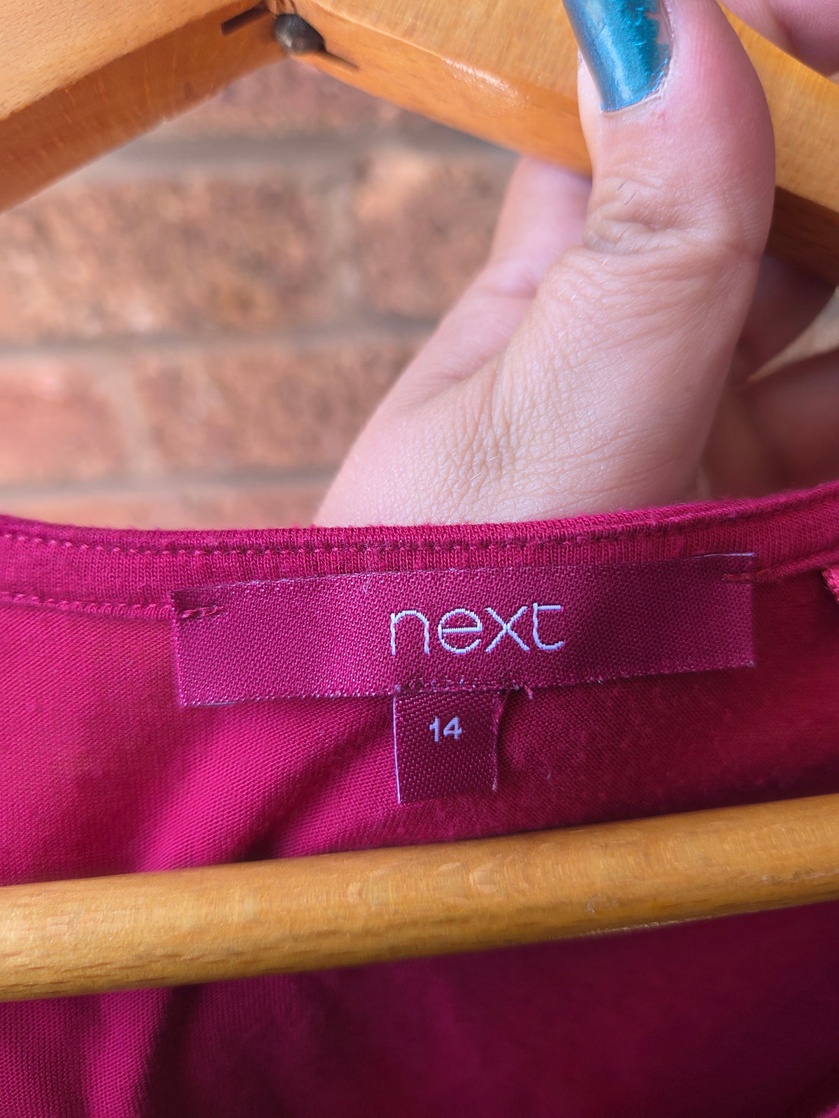 Close-up of Next brand label and size 14 tag inside neckline of burgundy vest top