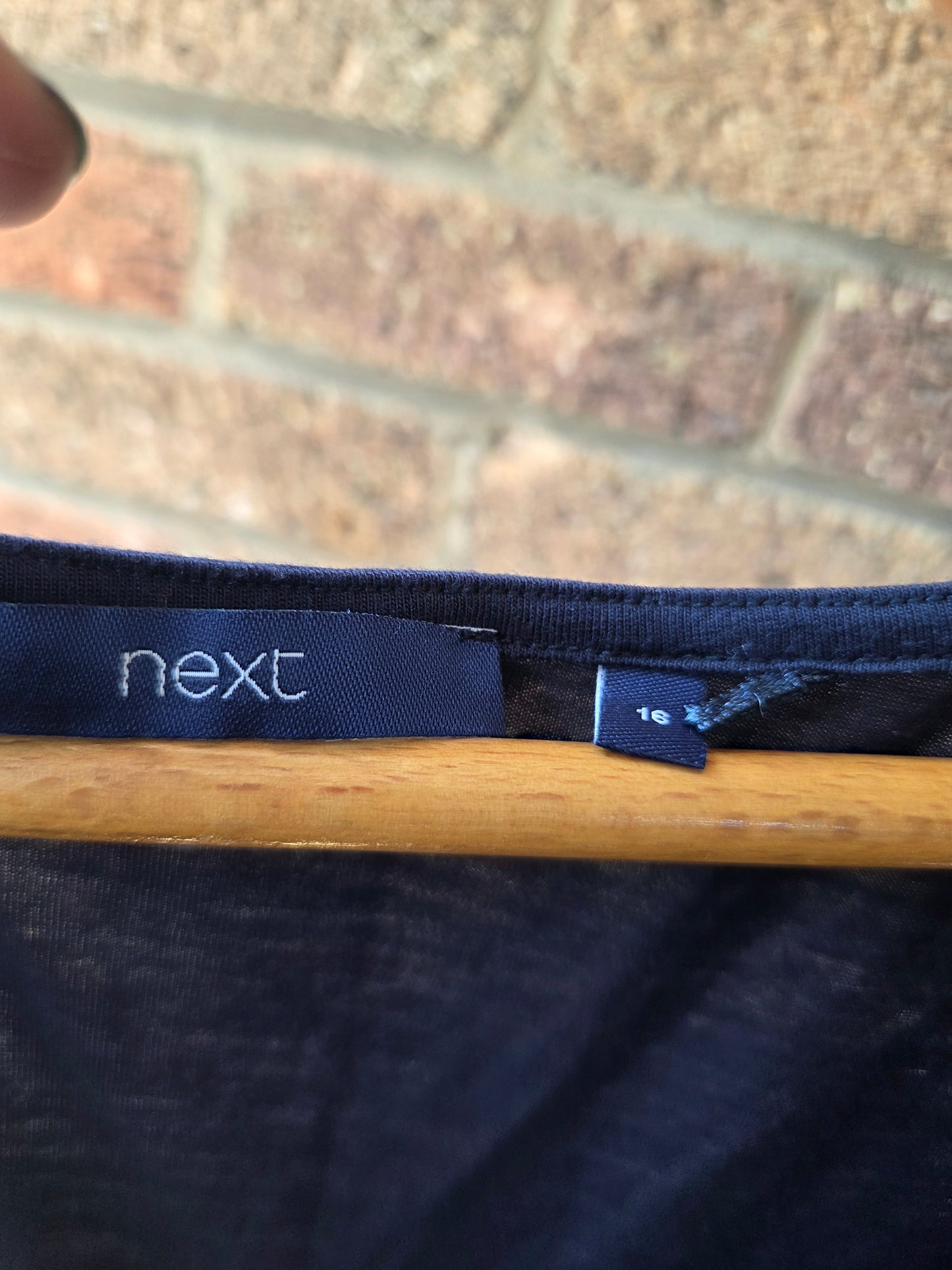 Close-up of Next brand label and size 16 tag inside neckline of navy vest top