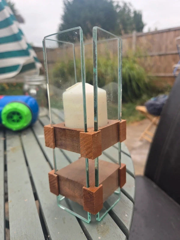 Glass and wood pillar candle holder - front view showing tall glass panels in chunky wooden jointed frame with white pillar candle inside